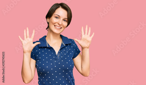 Young brunette woman with short hair wearing casual clothes showing and pointing up with fingers number ten while smiling confident and happy.
