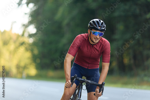 Smiling athlete in helmet and eyewear cycling on road