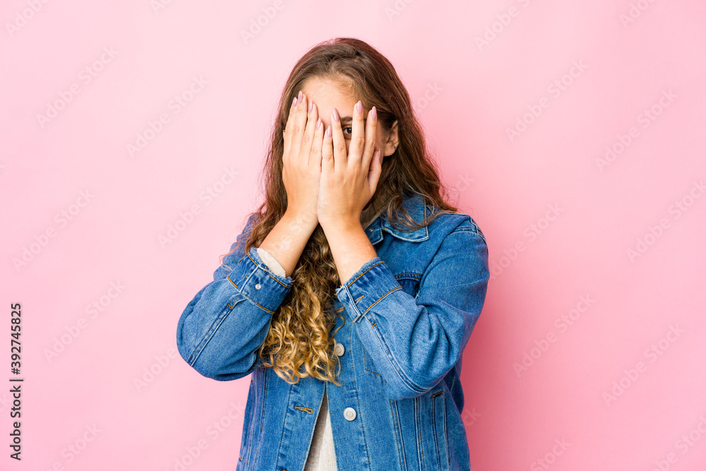 Young caucasian woman blink at the camera through fingers, embarrassed covering face. Young caucasian woman blink at the camera through fingers, embarrassed covering face.