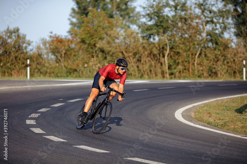 Fototapeta Naklejka Na Ścianę i Meble -  Strong athlete riding bike with high speed on road