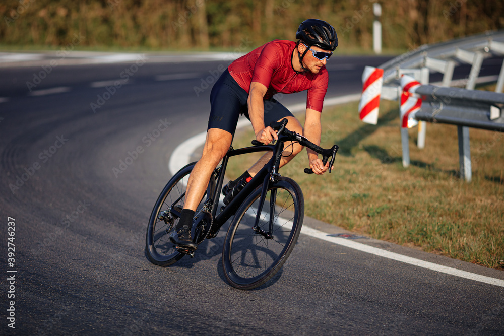 Male athlete in protective helmet biking on asphalt road