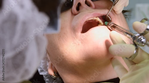 Dentist making local anaesthesia shot before surgery. Senior woman at dental clinic. Dentist with assistant install implant in a patient mouth in modern dental office