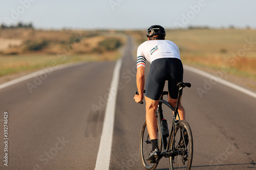 Active man riding black bike on asphalt road