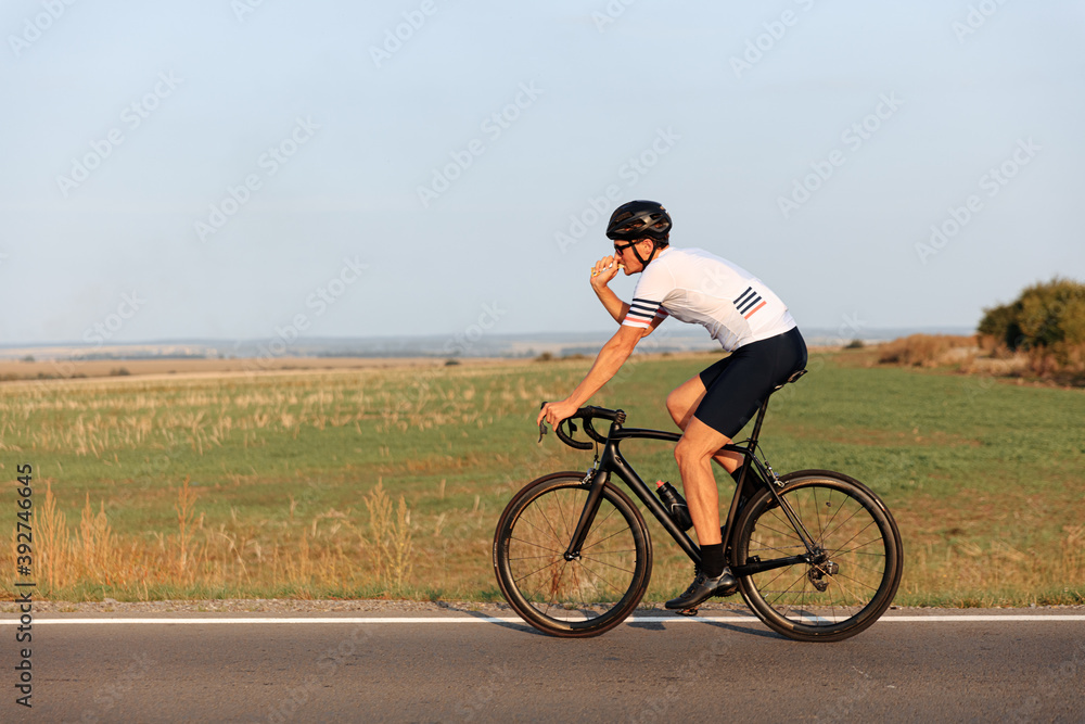 Sporty man with muscular body cycling on road