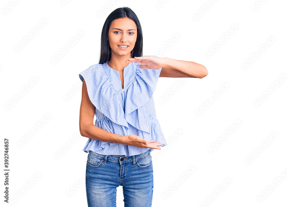 Young beautiful latin girl wearing casual clothes gesturing with hands showing big and large size sign, measure symbol. smiling looking at the camera. measuring concept. Young beautiful latin girl wearing casual clothes gesturing with hands showing big and large size sign, measure symbol. smiling looking at the camera. measuring concept.