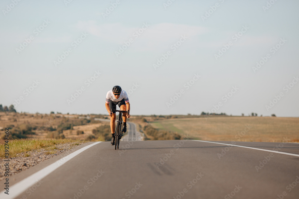 Young guy in activewear biking fast on paved road Young guy in activewear biking fast on paved road