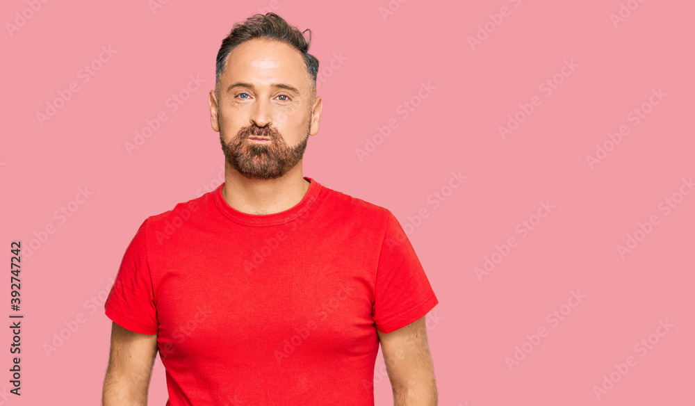 Handsome middle age man wearing casual red tshirt puffing cheeks with funny face. mouth inflated with air, crazy expression. Handsome middle age man wearing casual red tshirt puffing cheeks with funny face. mouth inflated with air, crazy expression.