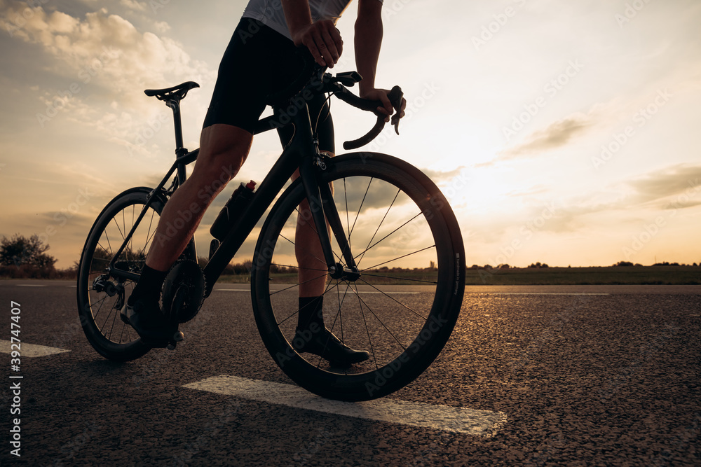 Close up of sporty young man standing on road with bike