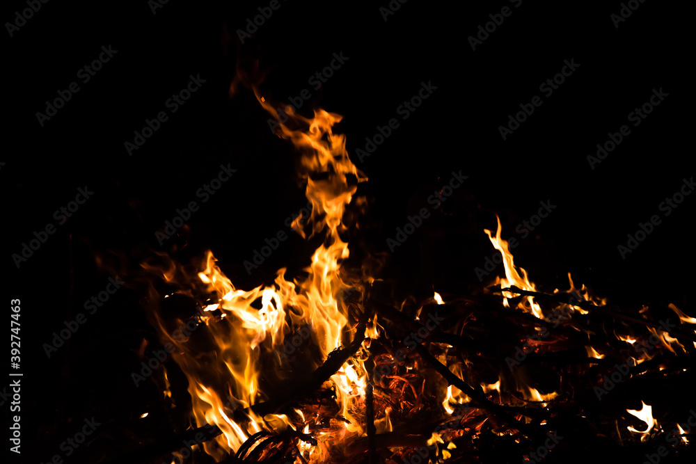 Burning red hot sparks rise from large fire in the night. Fire flames sparks background. Abstract dark glitter fire particles lights. Burning red hot sparks rise from large fire in the night. Fire flames sparks background. Abstract dark glitter fire particles lights.