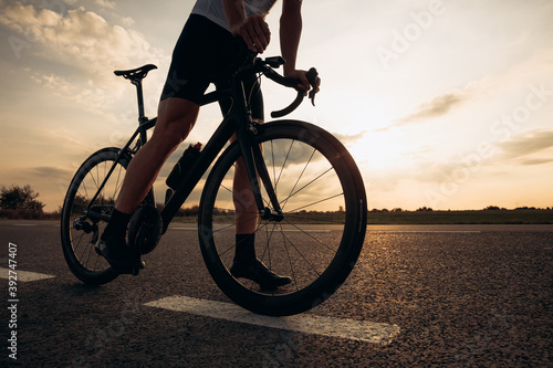 Fototapeta Naklejka Na Ścianę i Meble -  Close up of sporty young man standing on road with bike