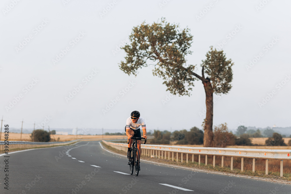 Athletic man in active clothing biking on asphalt road