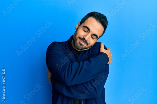 Young hispanic man with beard wearing casual clothes smiling with hand over ear listening and hearing to rumor or gossip. deafness concept. © Krakenimages.com