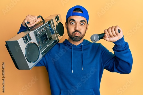 Young hispanic man with beard holding boombox listening to music singing with microphone skeptic and nervous, frowning upset because of problem. negative person.