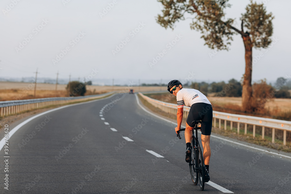 Young muscular guy in helmet riding bike on road Young muscular guy in helmet riding bike on road