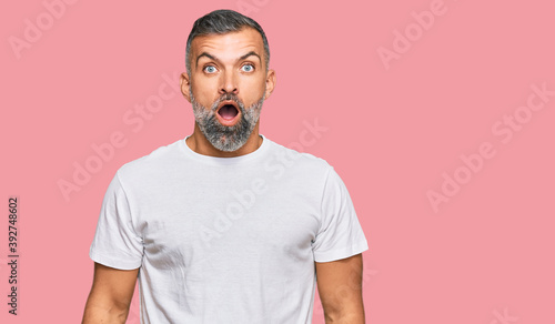 Fotografía Middle age handsome man wearing casual white tshirt afraid and shocked with surprise and amazed expression, fear and excited face