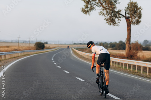 Fototapeta Naklejka Na Ścianę i Meble -  Young muscular guy in helmet riding bike on road