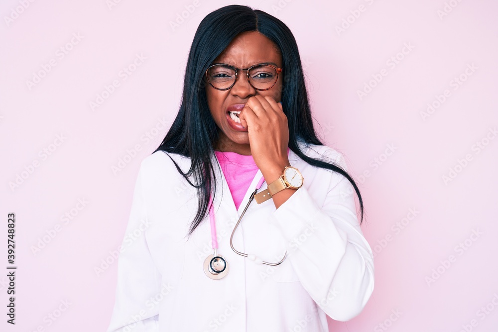 Young african american woman wearing doctor stethoscope looking stressed and nervous with hands on mouth biting nails. anxiety problem. Young african american woman wearing doctor stethoscope looking stressed and nervous with hands on mouth biting nails. anxiety problem.