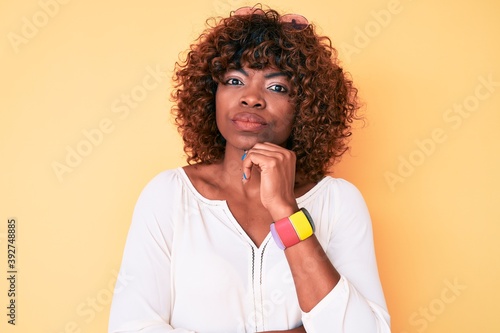 Young african american woman wearing casual clothes serious face thinking about question with hand on chin, thoughtful about confusing idea
