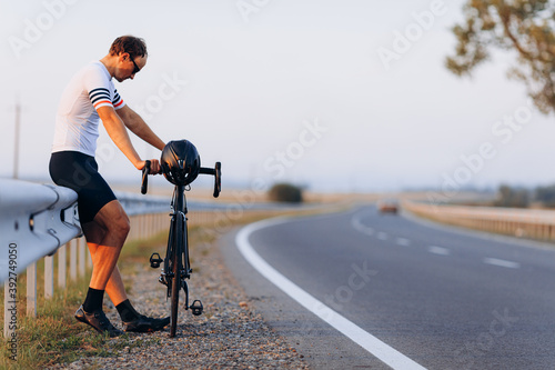 Side view of tired cyclist relaxing on road after riding