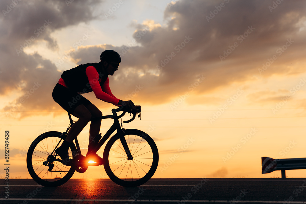 Side view of road cyclist training during amazing sunset Side view of road cyclist training during amazing sunset