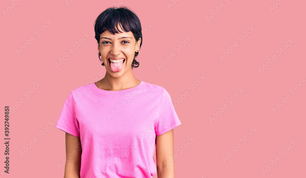Young brunette woman with short hair wearing casual clothes sticking tongue out happy with funny expression. emotion concept. Young brunette woman with short hair wearing casual clothes sticking tongue out happy with funny expression. emotion concept.