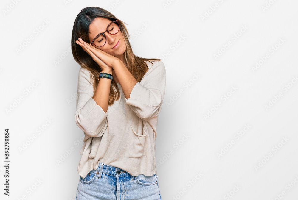 Young woman wearing casual clothes and glasses sleeping tired dreaming and posing with hands together while smiling with closed eyes. Young woman wearing casual clothes and glasses sleeping tired dreaming and posing with hands together while smiling with closed eyes.