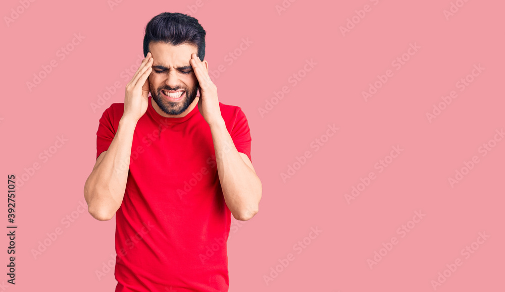 Young handsome man with beard wearing casual t-shirt with hand on head for pain in head because stress. suffering migraine. Young handsome man with beard wearing casual t-shirt with hand on head for pain in head because stress. suffering migraine.