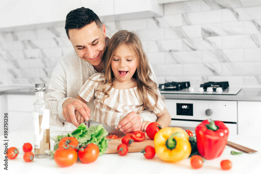 Father's day. Dad and his child daughter are cooking and having fun together in the kitchen. Family holiday. Father's day. Dad and his child daughter are cooking and having fun together in the kitchen. Family holiday.