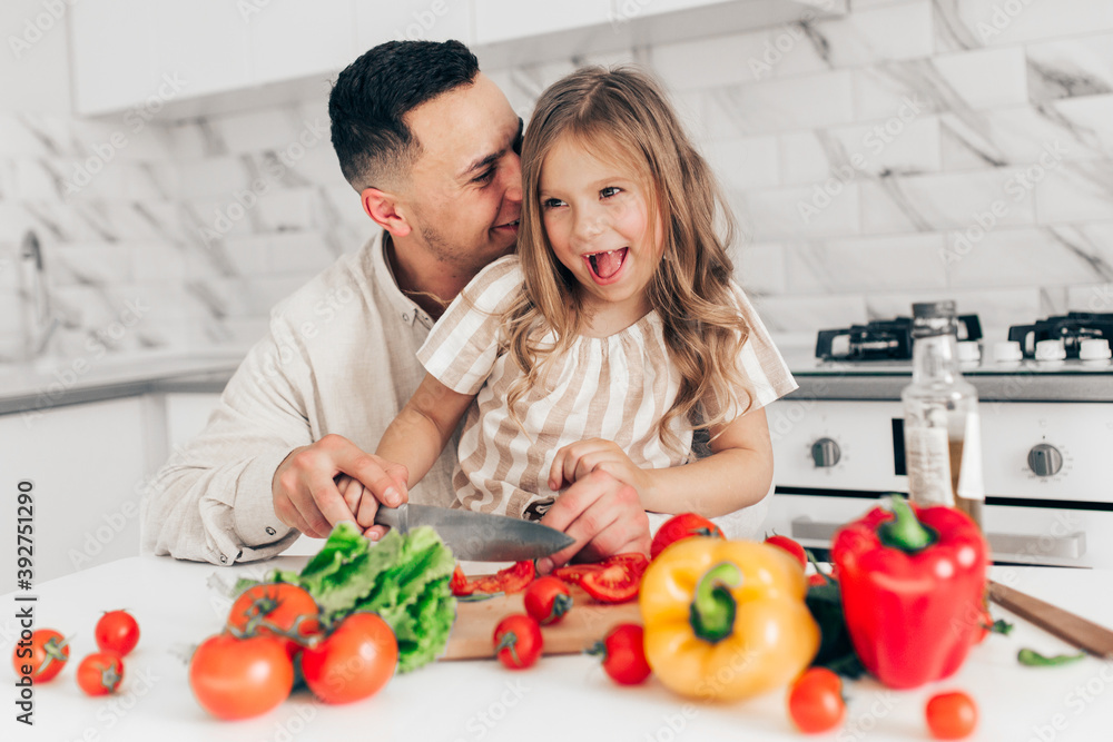 Father's day. Dad and his child daughter are cooking and having fun together in the kitchen. Family holiday. Father's day. Dad and his child daughter are cooking and having fun together in the kitchen. Family holiday.