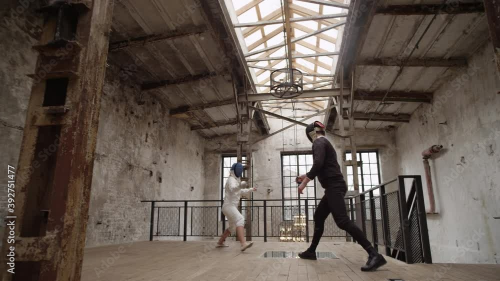 Fencer an angel in white fights with a demon fencer and defeats him by smashing him into the loft room of an old building. The concept of the victory of good. Slow motion Fencer an angel in white fights with a demon fencer and defeats him by smashing him into the loft room of an old building. The concept of the victory of good. Slow motion