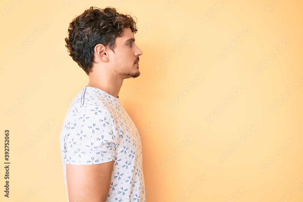 Young caucasian man with curly hair wearing casual clothes looking to side, relax profile pose with natural face with confident smile. Young caucasian man with curly hair wearing casual clothes looking to side, relax profile pose with natural face with confident smile.