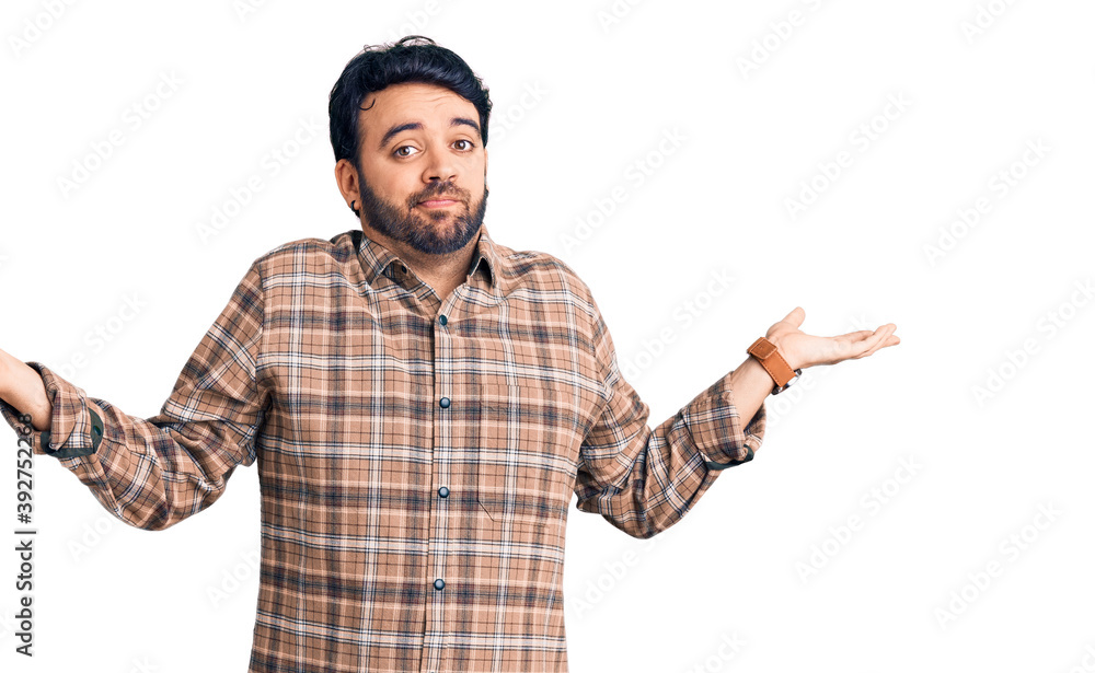Young hispanic man wearing casual clothes clueless and confused expression with arms and hands raised. doubt concept. Young hispanic man wearing casual clothes clueless and confused expression with arms and hands raised. doubt concept.