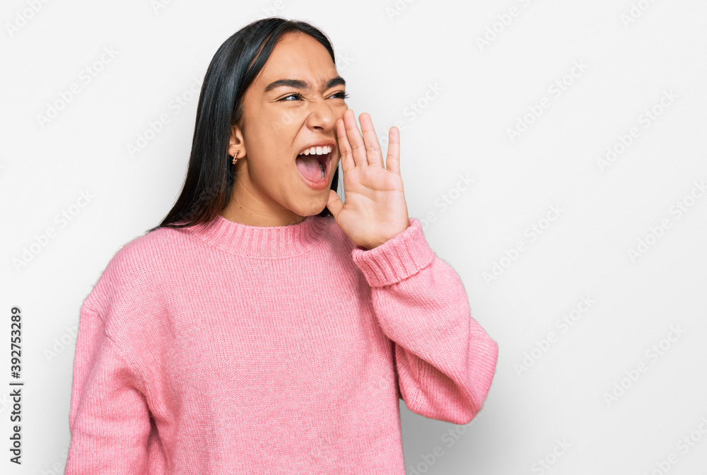 Young asian woman wearing casual winter sweater shouting and screaming loud to side with hand on mouth. communication concept. Young asian woman wearing casual winter sweater shouting and screaming loud to side with hand on mouth. communication concept.