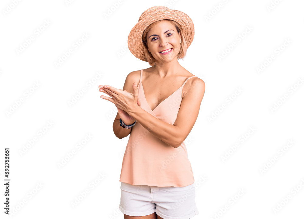 Young blonde woman wearing summer hat clapping and applauding happy and joyful, smiling proud hands together Young blonde woman wearing summer hat clapping and applauding happy and joyful, smiling proud hands together