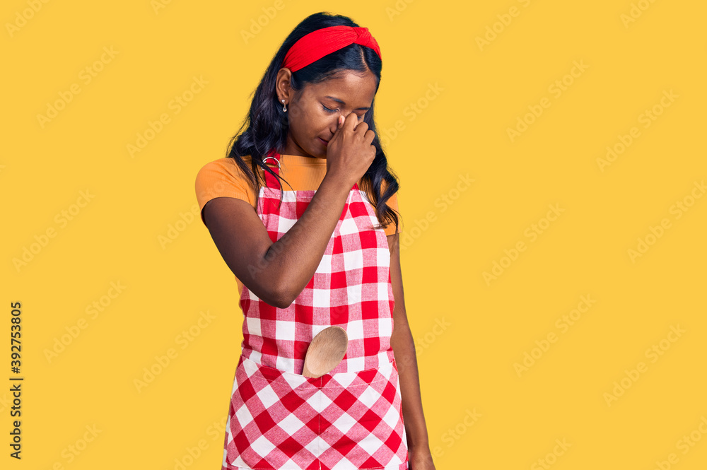 Young indian girl wearing professional baker apron tired rubbing nose and eyes feeling fatigue and headache. stress and frustration concept. Young indian girl wearing professional baker apron tired rubbing nose and eyes feeling fatigue and headache. stress and frustration concept.