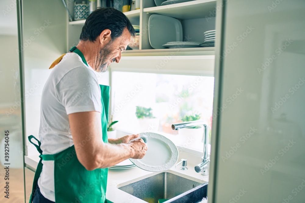 Middle age man with beard smiling happy washing dishes at home Middle age man with beard smiling happy washing dishes at home
