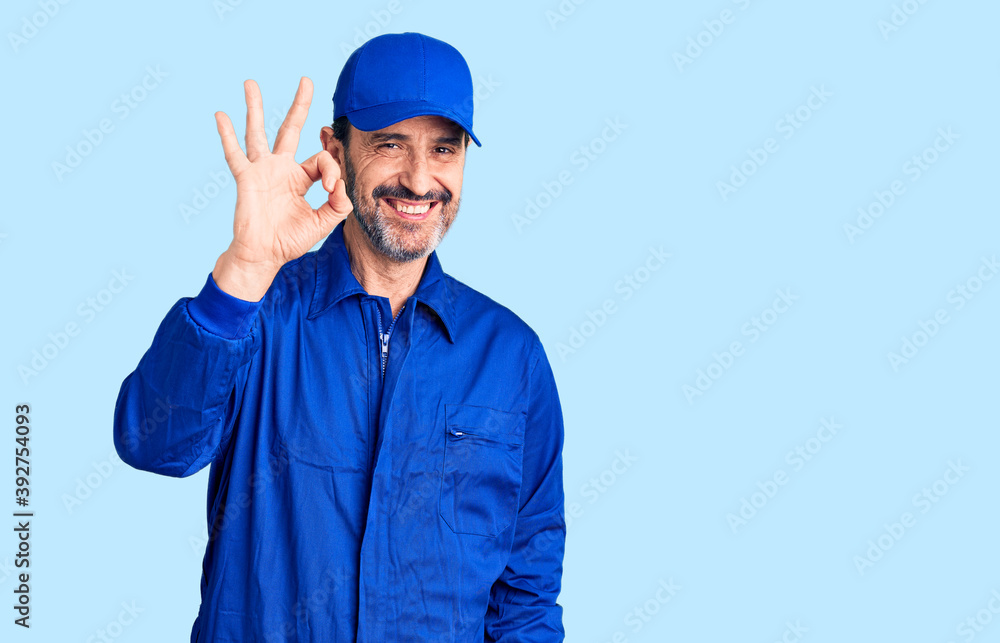 Middle age handsome man wearing mechanic uniform smiling positive doing ok sign with hand and fingers. successful expression.