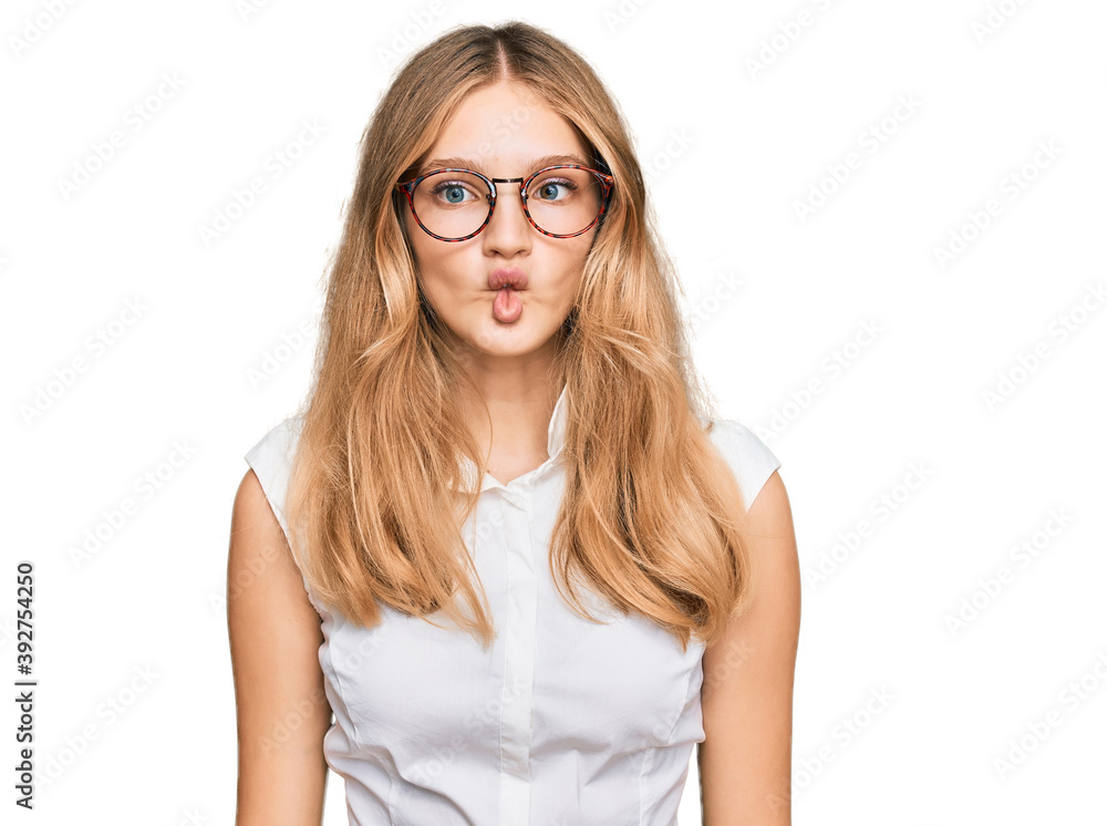Beautiful young caucasian girl wearing casual clothes and glasses making fish face with lips, crazy and comical gesture. funny expression. Beautiful young caucasian girl wearing casual clothes and glasses making fish face with lips, crazy and comical gesture. funny expression.