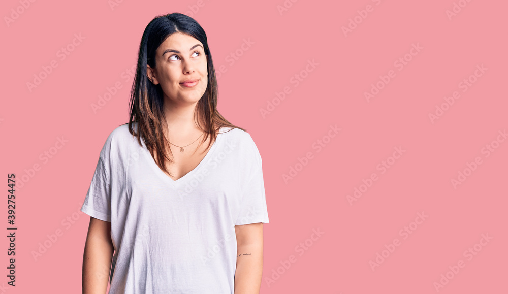 Young beautiful brunette woman wearing casual t-shirt smiling looking to the side and staring away thinking.