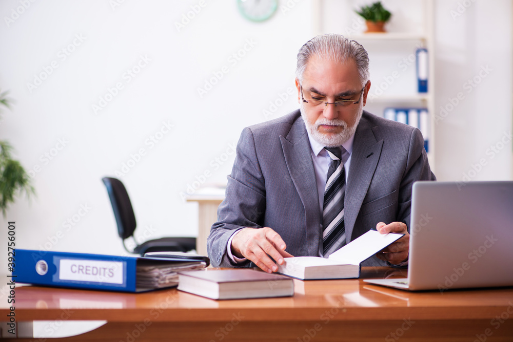 Old male businessman employee reading guidelines in the office Old male businessman employee reading guidelines in the office