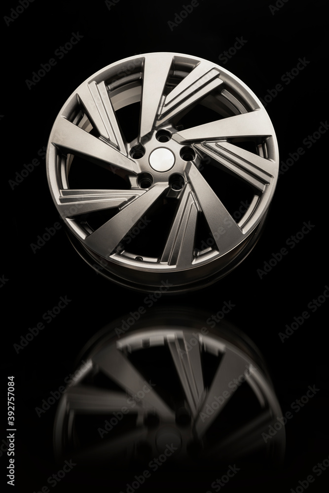 Alloy wheel close-up on a black background. Beautiful grey wheel color and reflection, vertical photo.