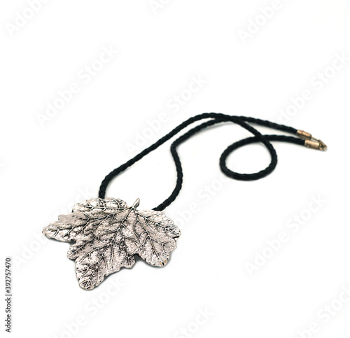 Silver large female pendant in the form of a maple leaf, close-up on a white background.