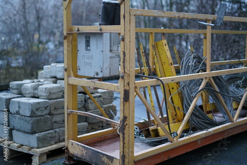 Construction crane for lifting workers to the building. Building blocks are being cut nearby.