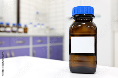 Фотография Selective focus of dark glass reagent bottle with unknown clear liquid chemical