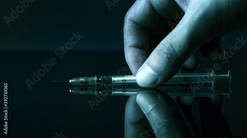The drug addict takes the syringe from the table. Macro