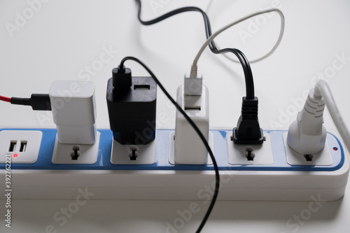 A lot of electric cable plugged in socket. Risk of electric shock Overload. Electrical equipment, electrical wires and power strips on the wall.