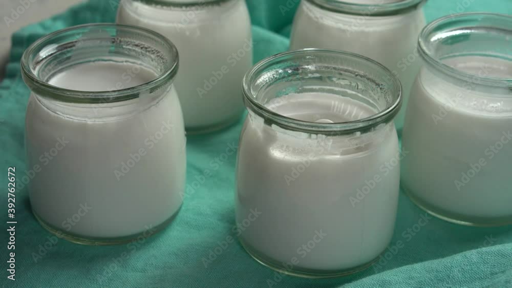 Homemade yogurt in glass jars. Yogurt on turquoise fabric. Tasting yogurt with a teaspoon. Coconut yogurt for proper nutrition, weight loss Homemade yogurt in glass jars. Yogurt on turquoise fabric. Tasting yogurt with a teaspoon. Coconut yogurt for proper nutrition, weight loss
