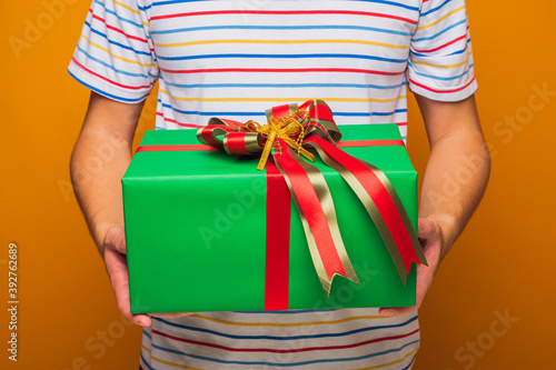 Close up male hands holding present gift box showing into camera. Merry christmas and Happy new year festival.
