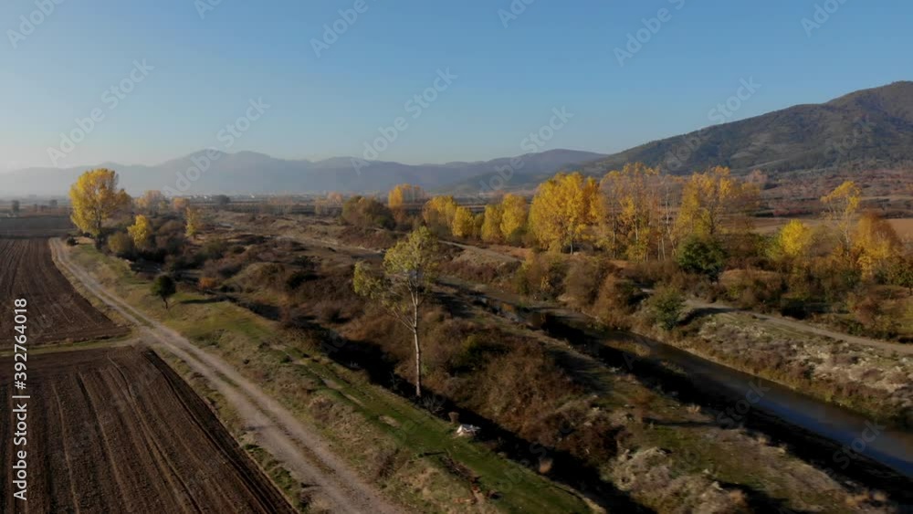 Countryside at morning, yellow trees and river streaming through land ready to be planted Countryside at morning, yellow trees and river streaming through land ready to be planted