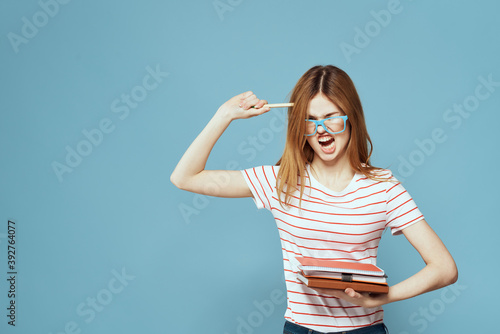 girl in fashionable glasses with notebooks in hands on a blue background cropped view Copy Space